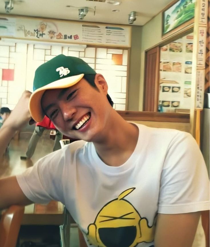 a young man sitting at a table with food in front of him and smiling for the camera