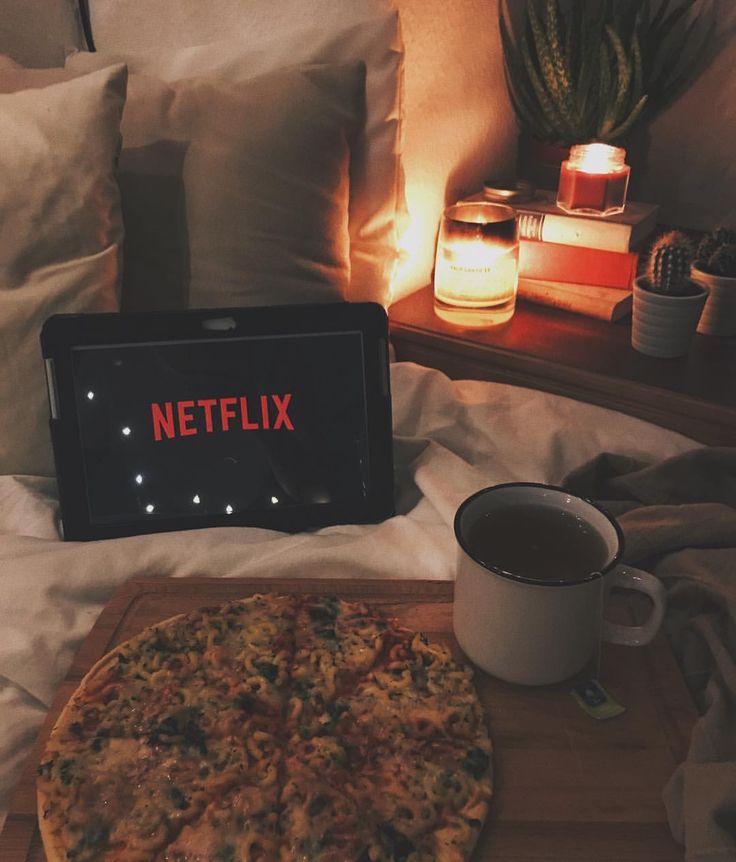 a pizza sitting on top of a wooden cutting board next to a cup of coffee