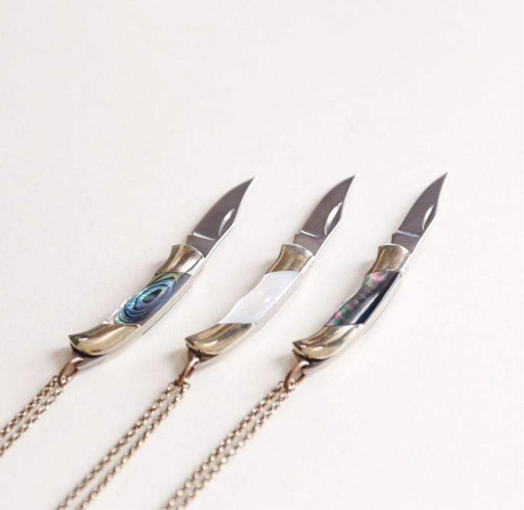 four knives with chains attached to them on a white surface