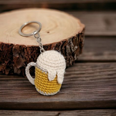 a crocheted beer mug keychain is shown on a piece of wood