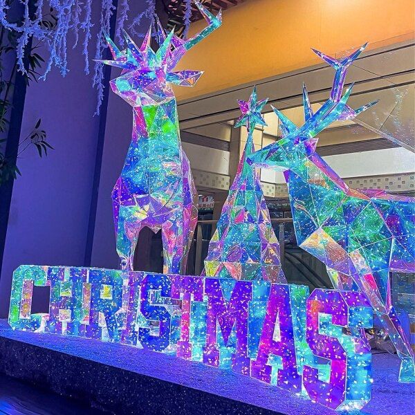 a lighted sign that says christmas and two deers in front of it with snowflakes hanging from the ceiling