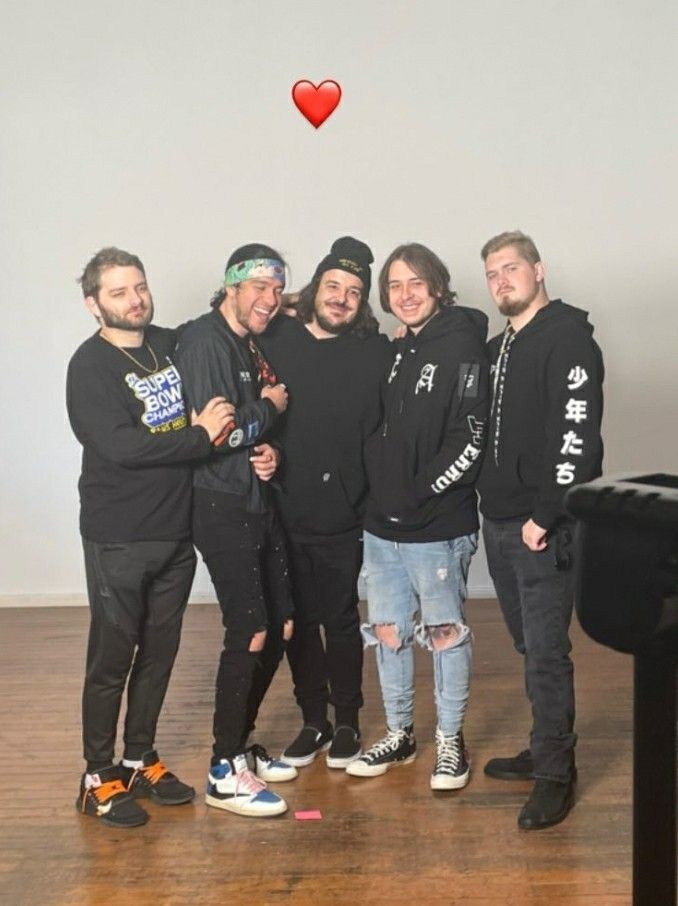 a group of young men standing next to each other in front of a heart shaped balloon