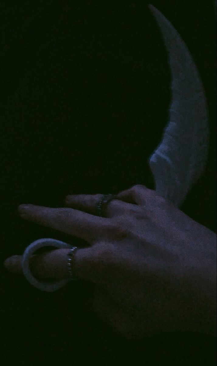 a person's hand with two rings and a ring on their finger in the dark