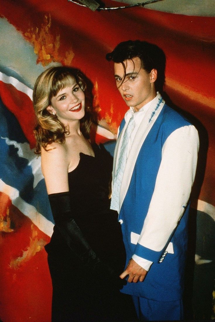 a man and woman standing next to each other in front of a british flag wall