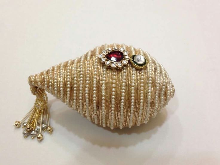 a close up of a brooch on a white surface with beads and tassels