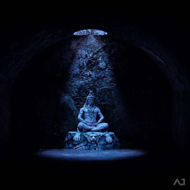 a buddha statue sitting in the middle of a dark tunnel with light coming from it