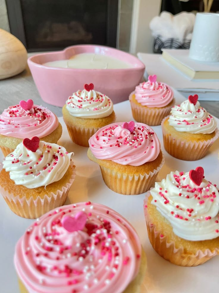 cupcakes with white frosting and pink sprinkles on a table