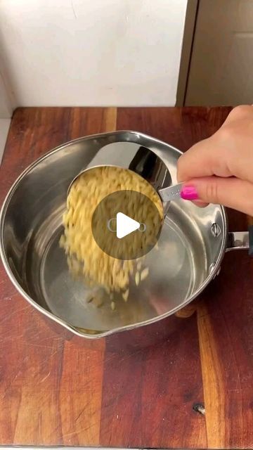 a person using a spatula to stir food in a pan on a wooden table