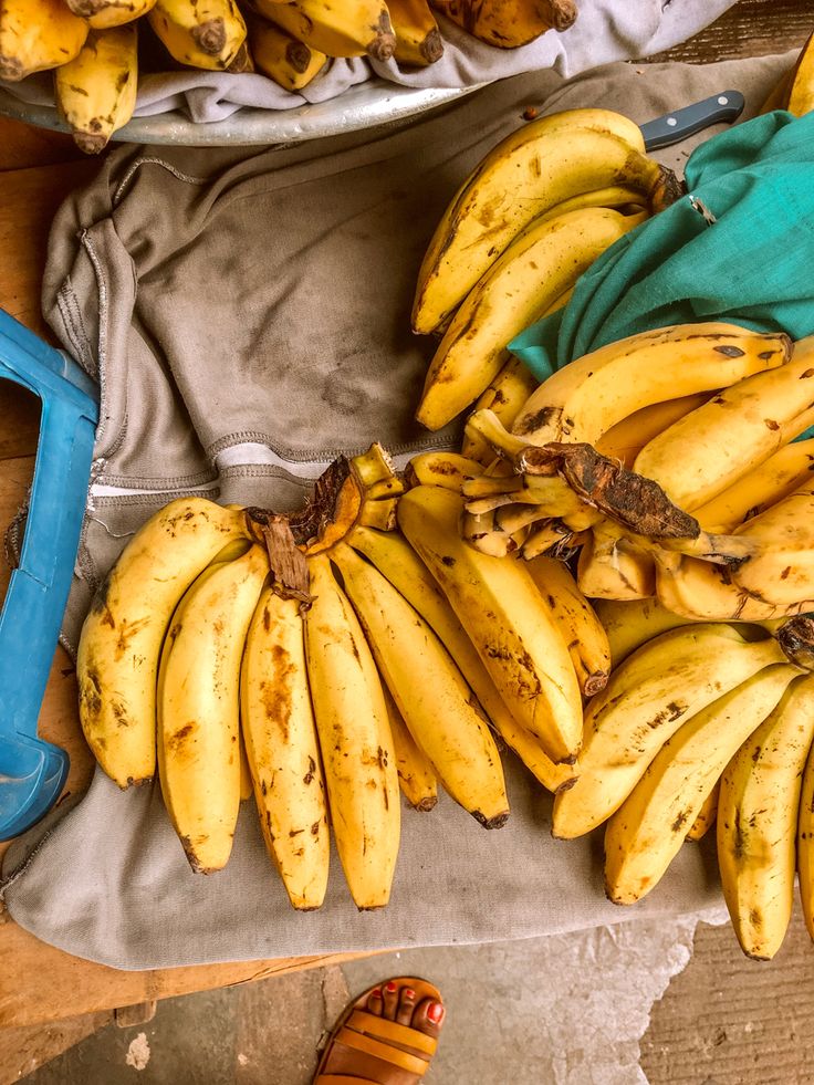 several bunches of bananas sitting on top of a table next to a pair of scissors