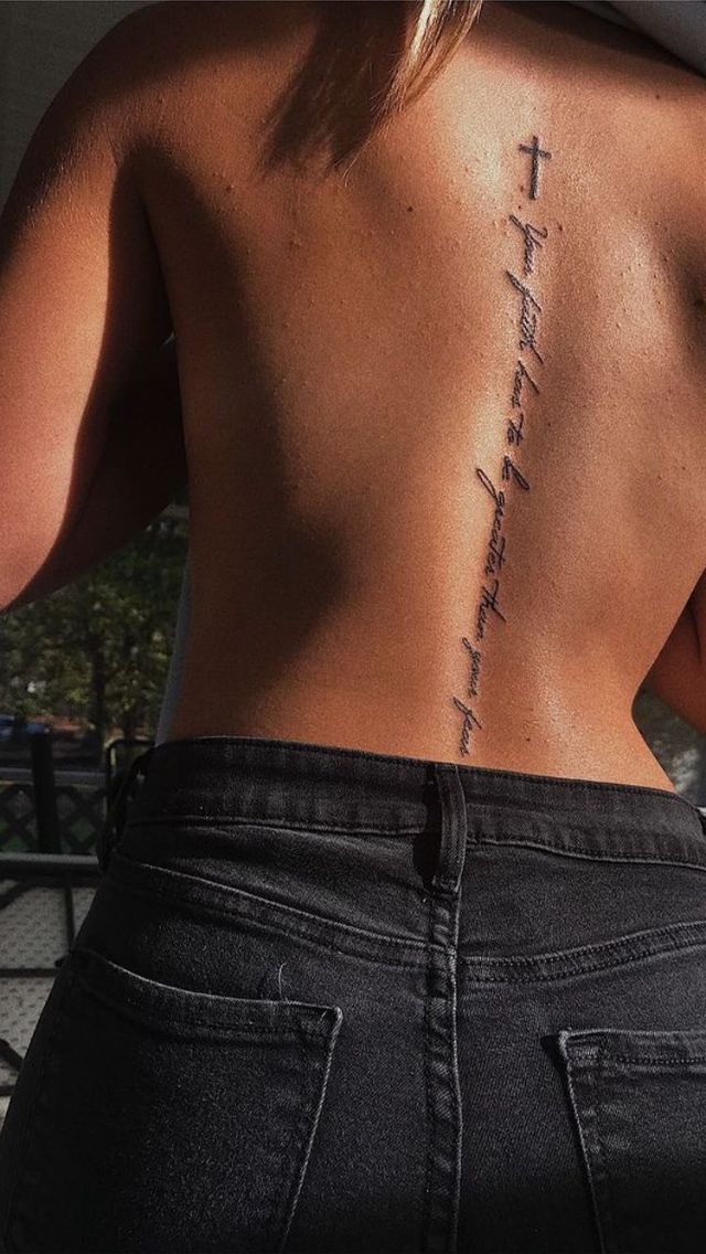 the back of a woman's body with a cross tattoo on it