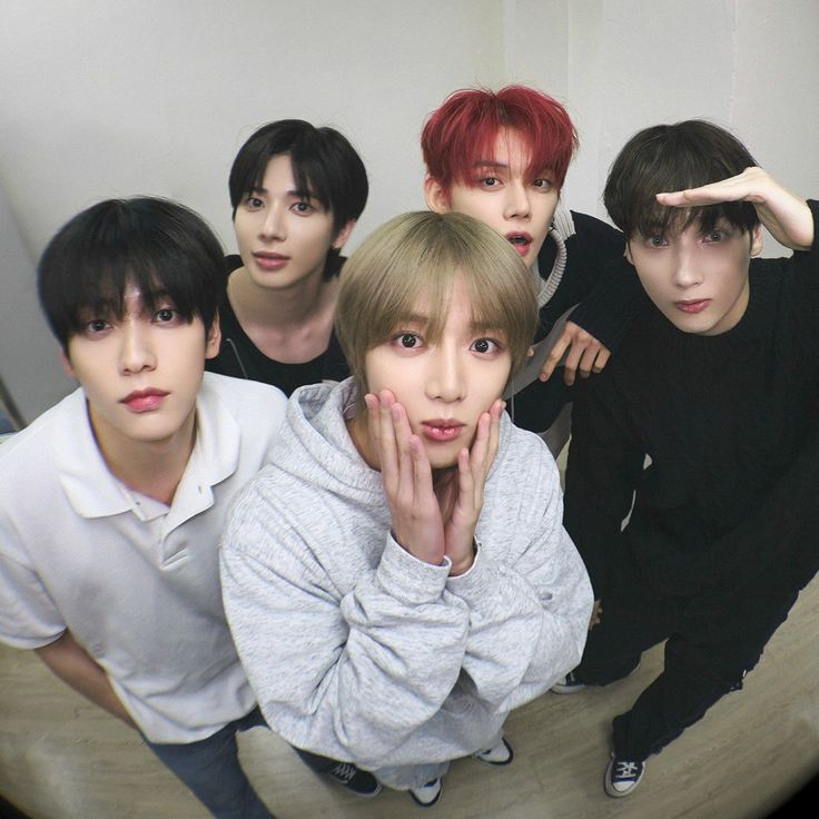 four boys are posing for a photo in front of a mirror with their hands on their face