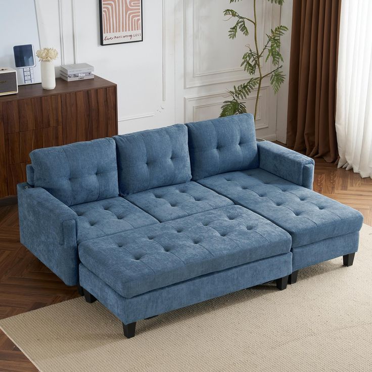 a blue sectional couch sitting on top of a rug in front of a wooden table