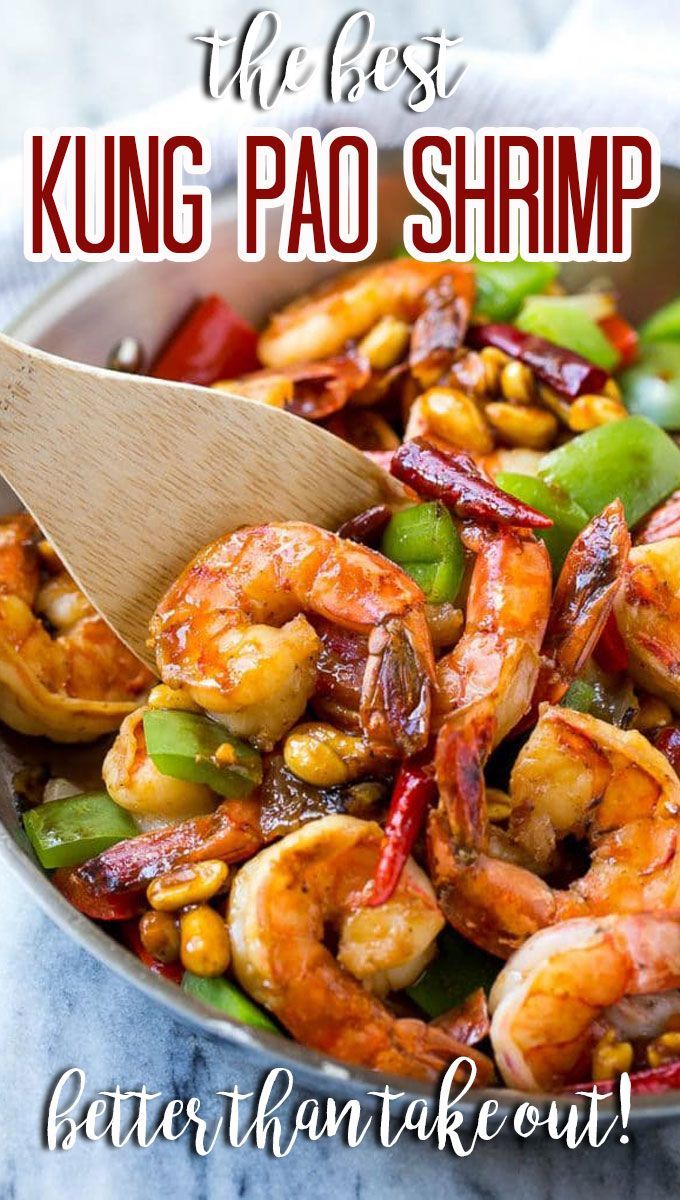 a skillet filled with shrimp, bell pepper and green peppers next to a wooden spoon