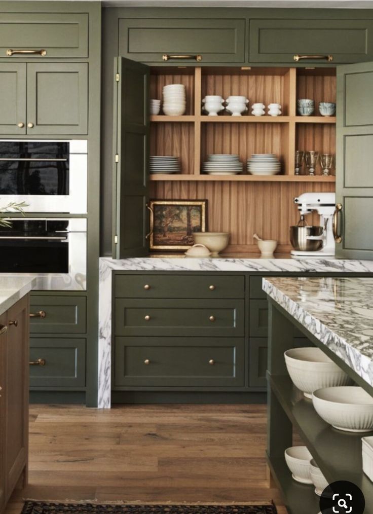 a kitchen filled with lots of green cabinets and counter top space next to an oven