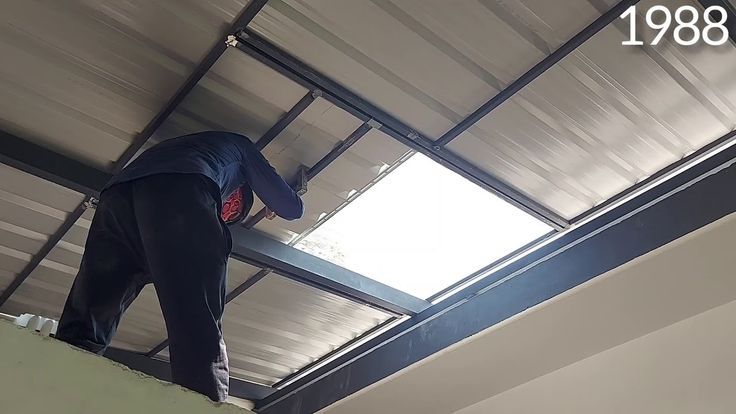 a man standing on top of a roof in a room filled with metal beams and windows