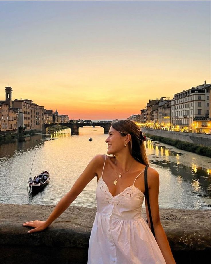 a woman in a white dress standing next to a river