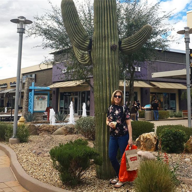 a woman standing next to a tall cactus