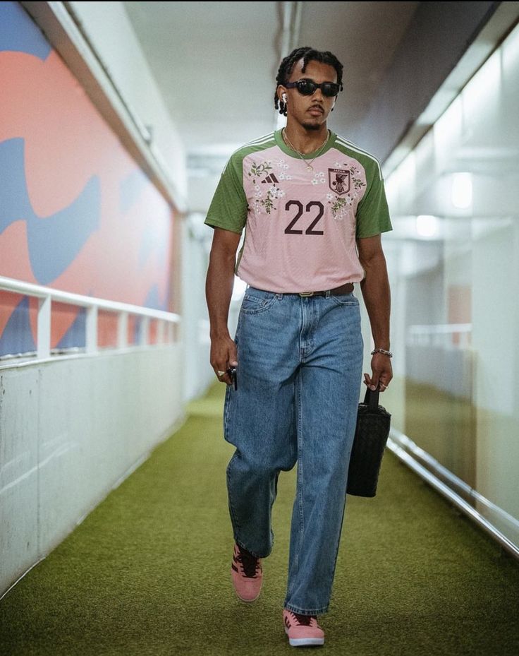 a man walking down a hallway carrying a black bag and wearing pink converse shoes with his hand in his pocket