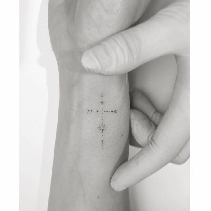 a woman's arm with a small cross tattoo on the left side of her wrist