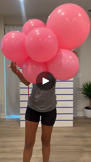 a woman holding pink balloons in her hands