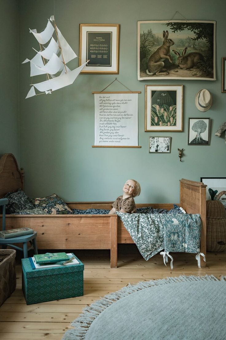 a child's room with green walls and pictures on the wall, including a bed