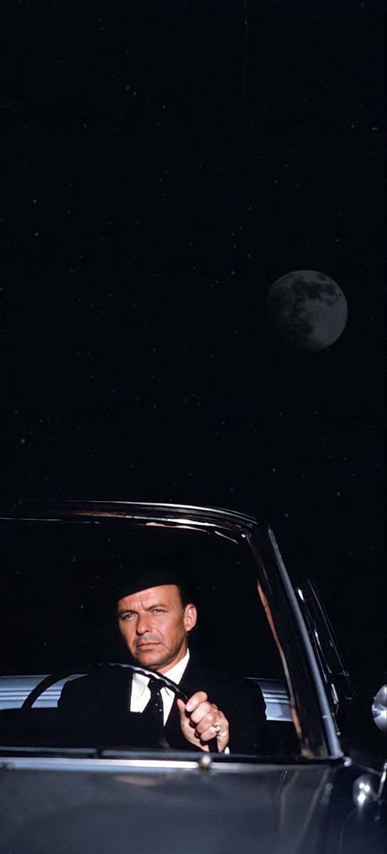 a man in a tuxedo sitting in a car with the moon behind him