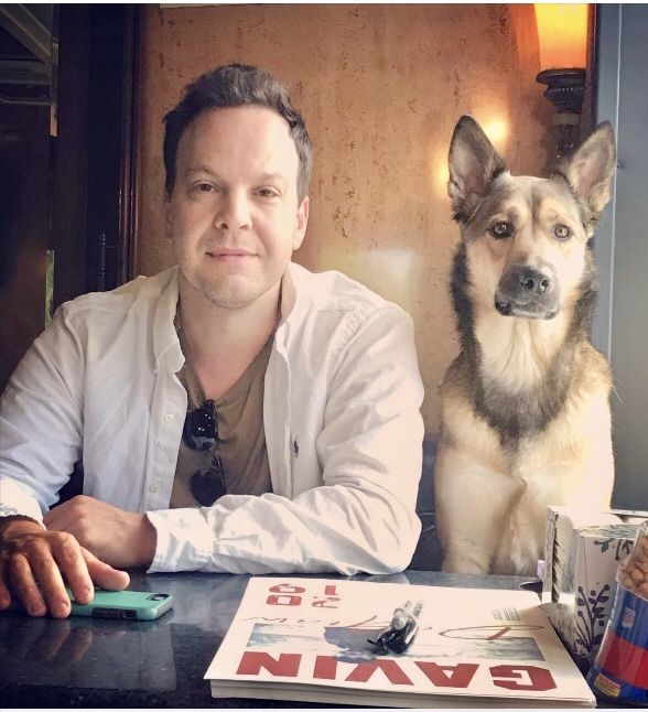 a man sitting at a table next to a dog