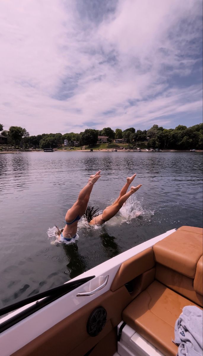 a woman is swimming in the water on a boat with her feet up and arms out