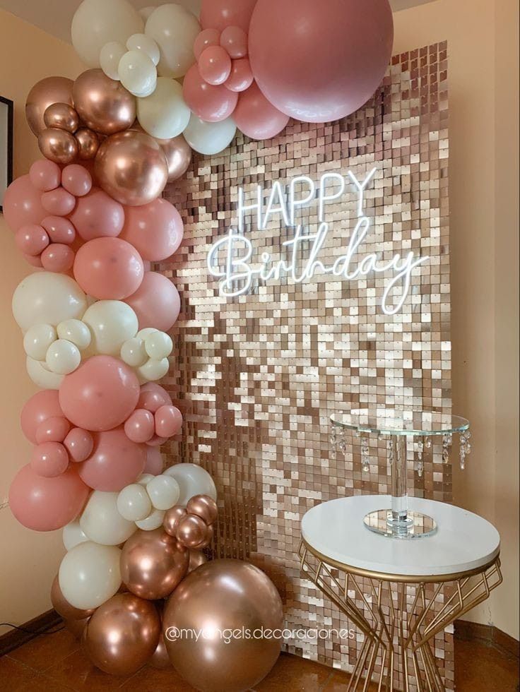 a birthday party with balloons and confetti on the wall in front of it