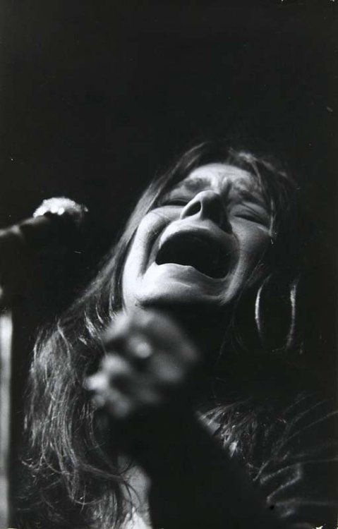 a woman singing into a microphone with her mouth open