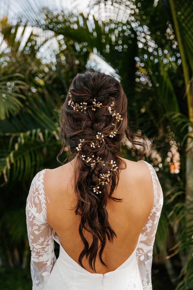 the back of a woman's head wearing a wedding dress and gold hair pins