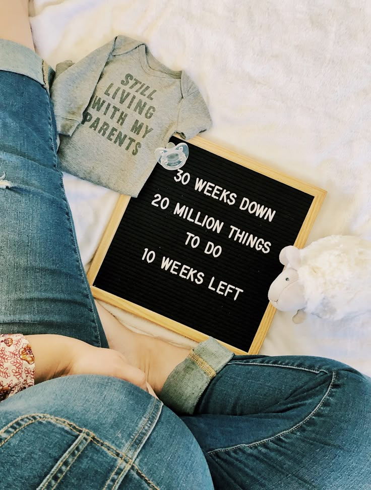 a woman laying on top of a bed next to a blackboard that says 30 weeks down 20 million things to do 10 years left