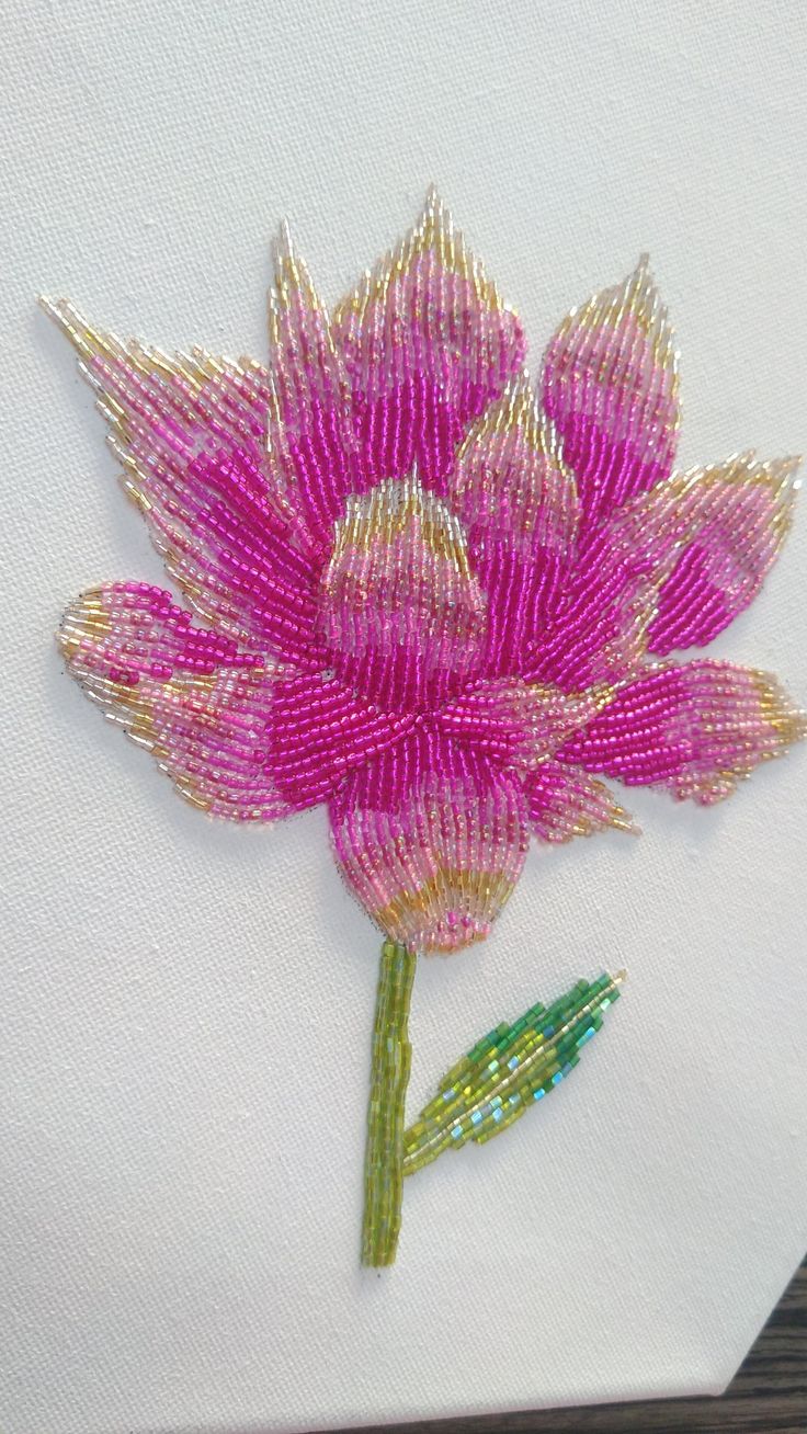 a pink flower is embroidered onto a white piece of paper