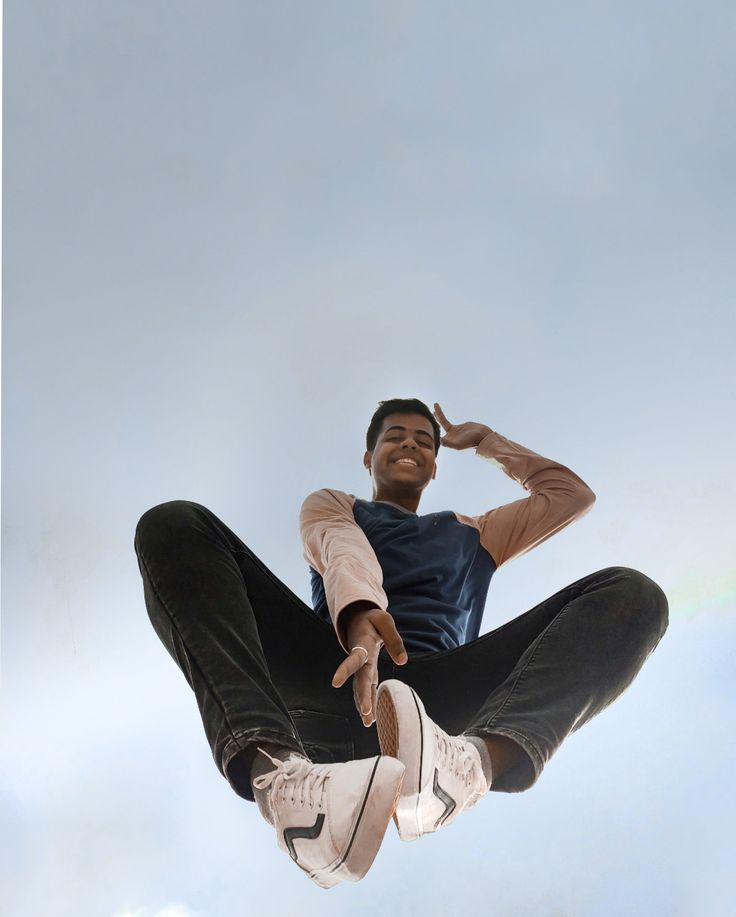 a man flying through the air while riding on top of a skateboard in front of a blue sky