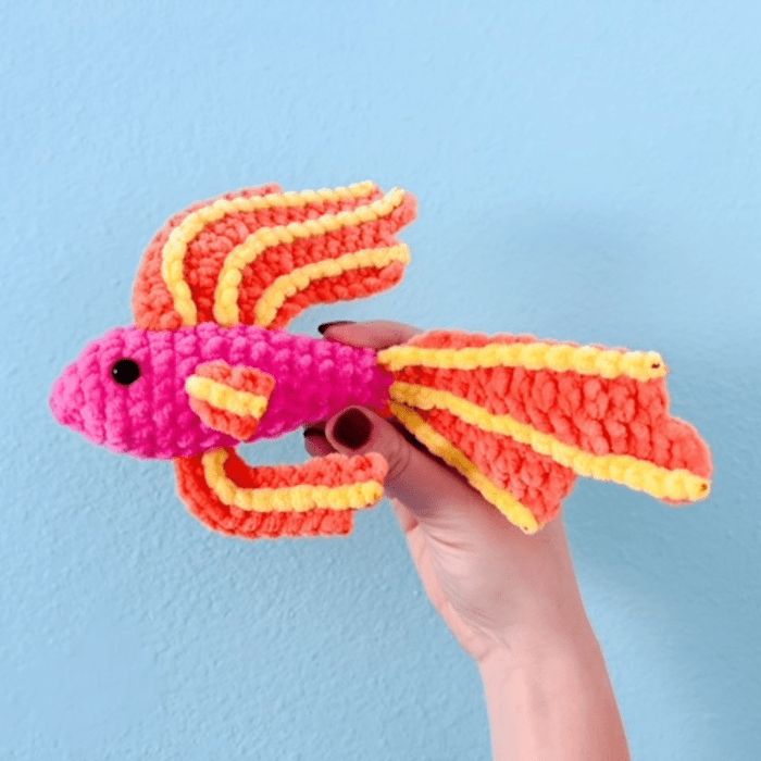 a hand is holding a small toy that looks like a fish