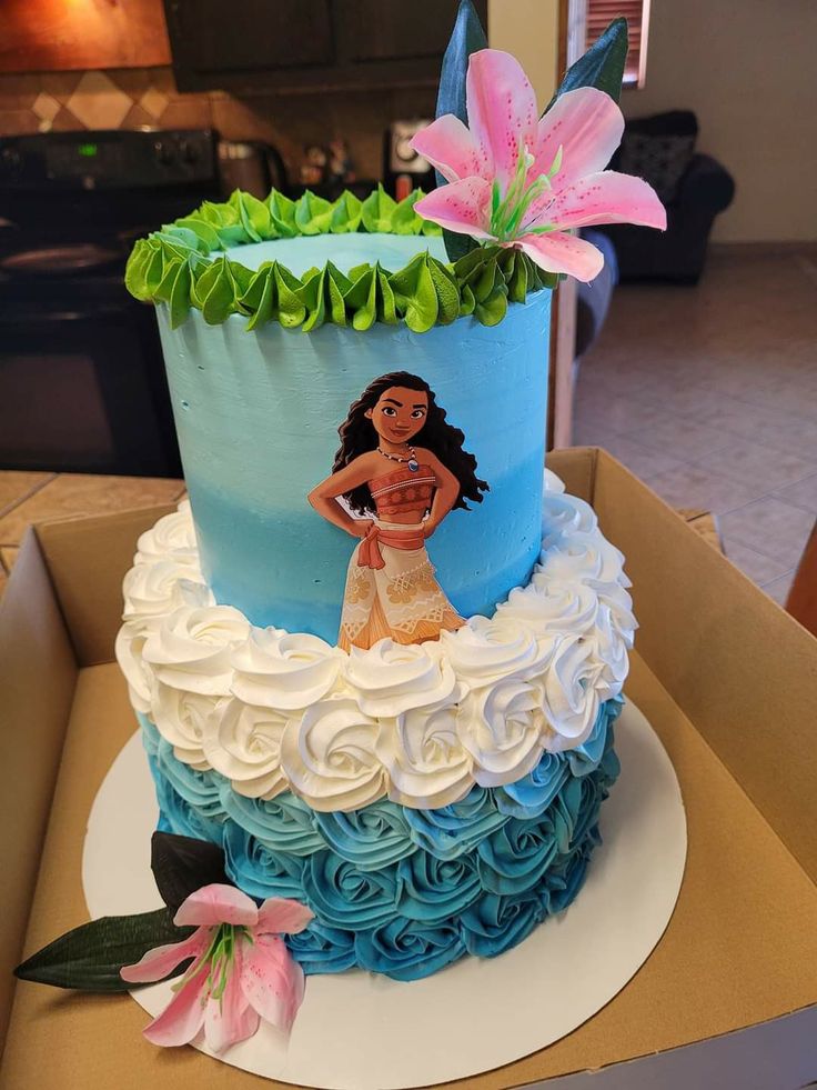 the cake is decorated with blue and white icing, flowers, and a hula girl on top