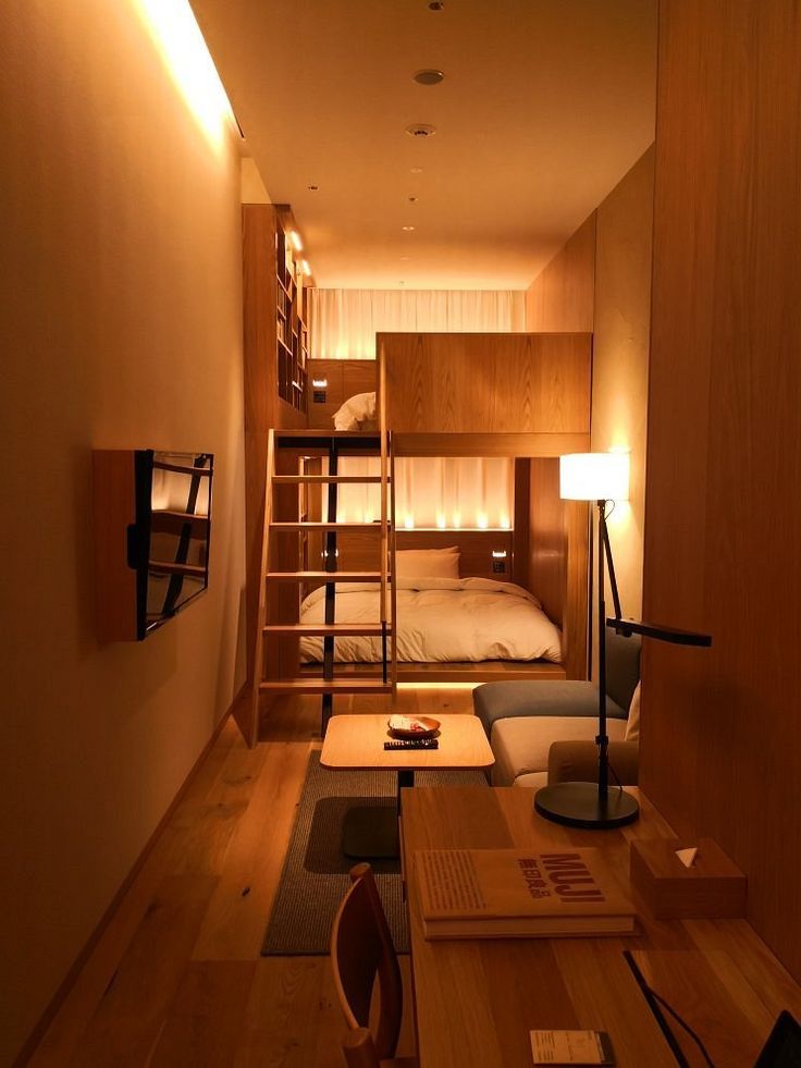 a small room with bunk beds and a ladder to the top floor, in front of a bed