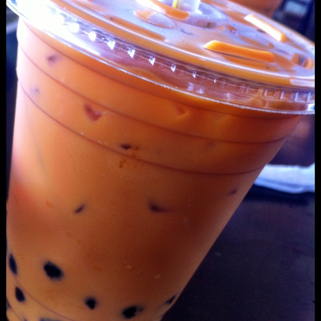 an orange drink in a plastic cup with straws on the rim and black dots