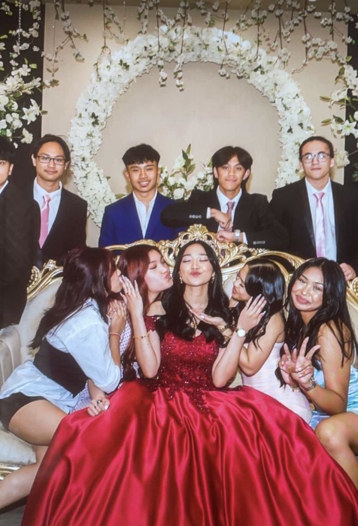 a group of young people posing for a photo in front of a backdrop with flowers