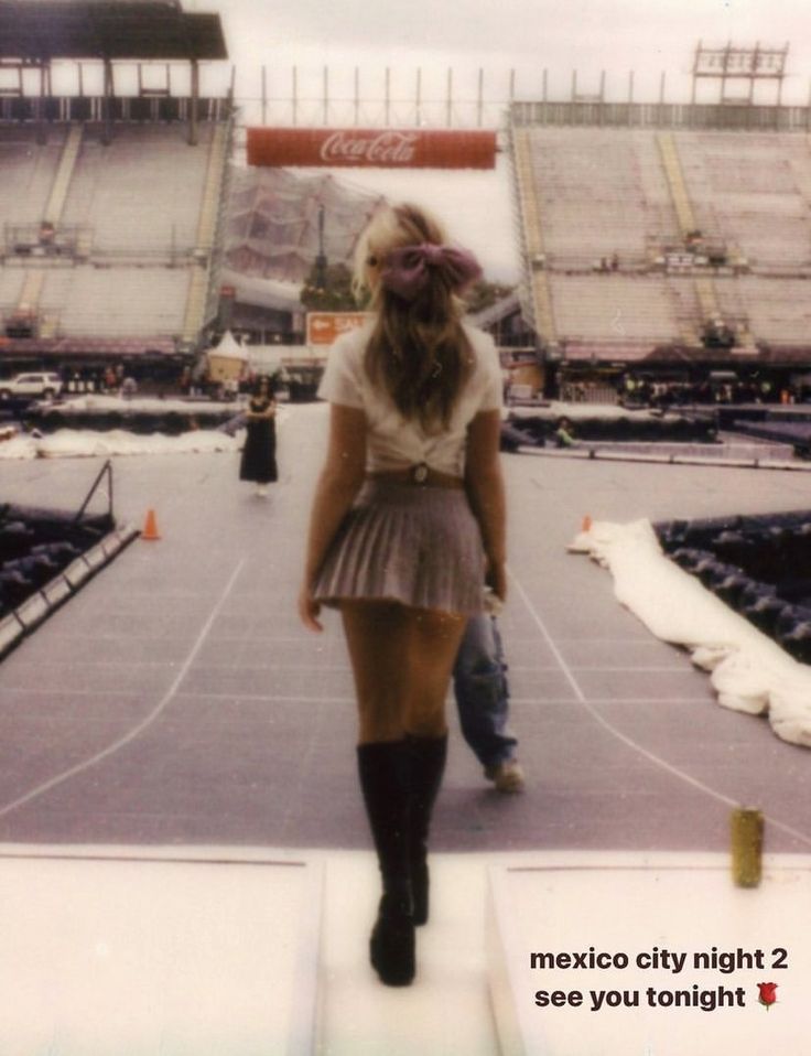 a woman in a short skirt and knee high boots is walking on the stage at a stadium