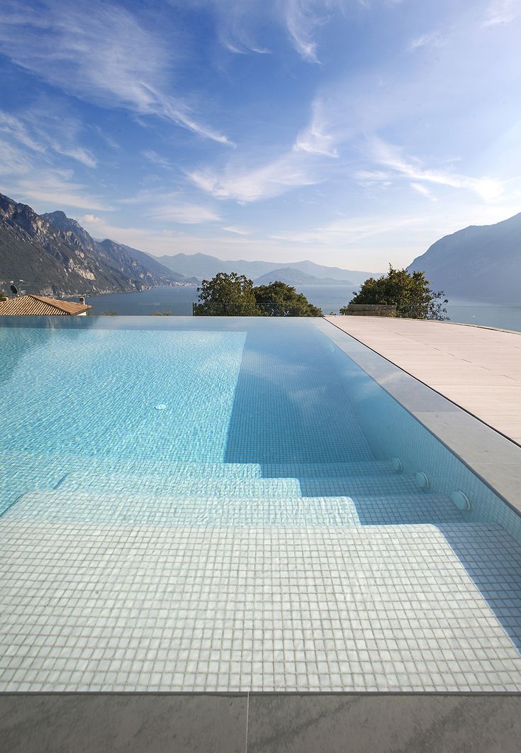 an empty swimming pool with mountains in the background and blue skies above, on a sunny day