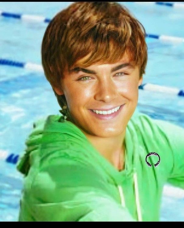 a young man in a green shirt is posing for a photo by the swimming pool