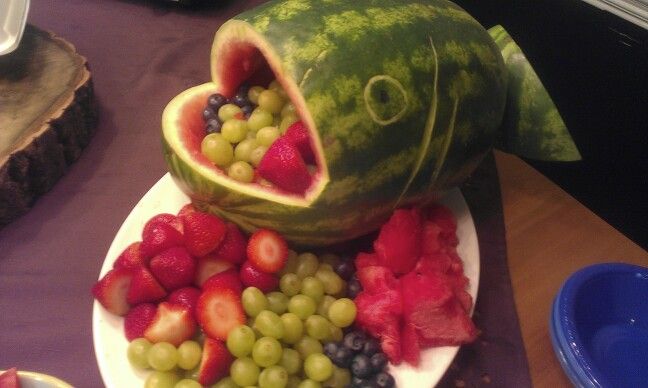 a watermelon shaped like a fish with grapes and strawberries in it's mouth