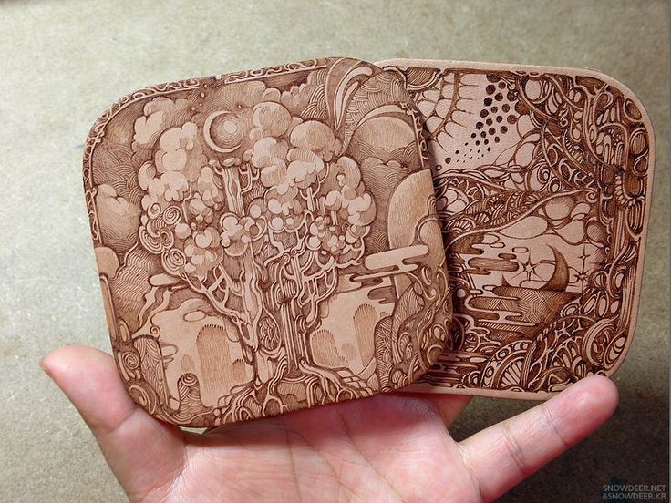 two wooden coasters with designs on them in the palm of someone's hand