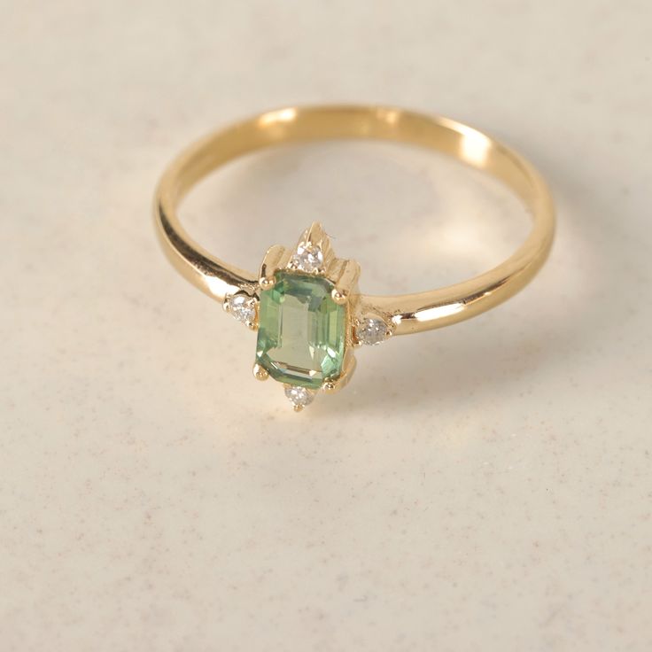 an emerald and diamond ring on a white surface