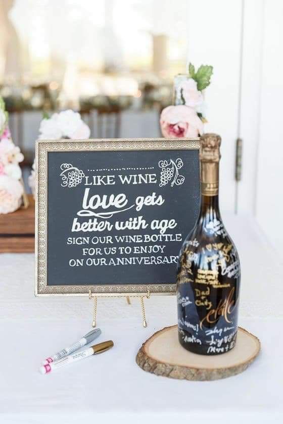 a bottle of wine sitting on top of a table next to a chalkboard sign