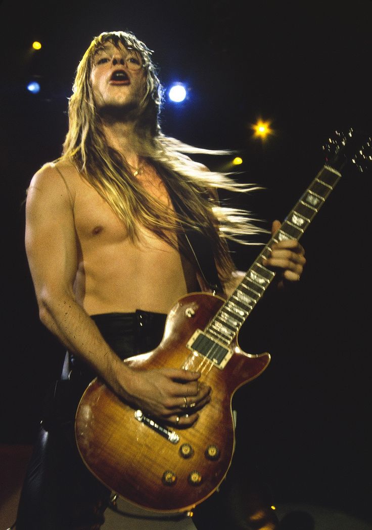 a man with long hair playing an electric guitar