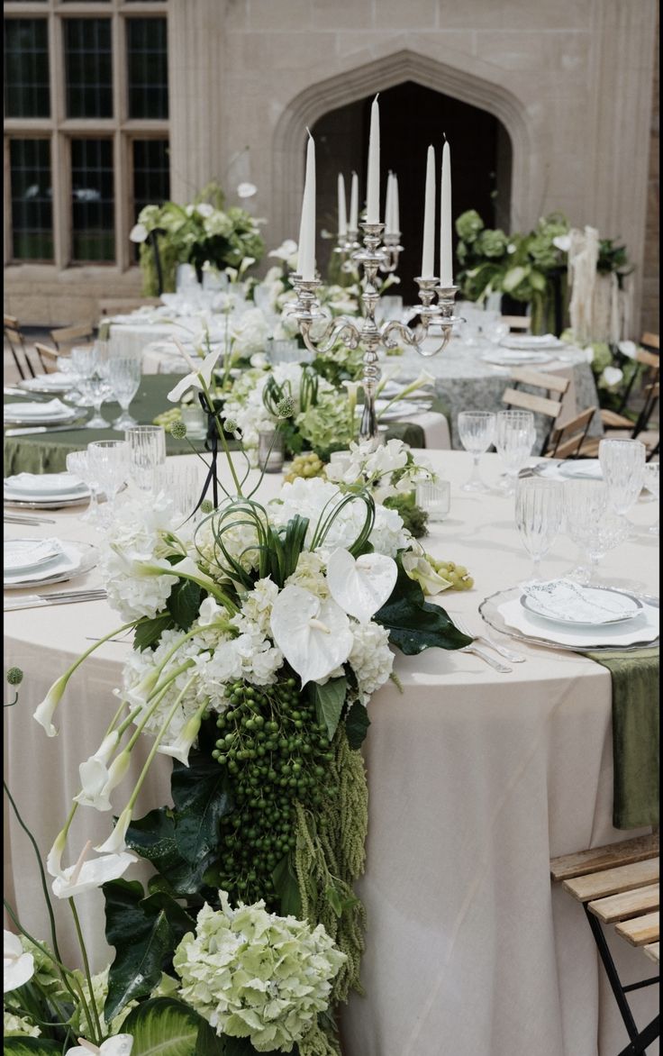 the table is set with white flowers and greenery