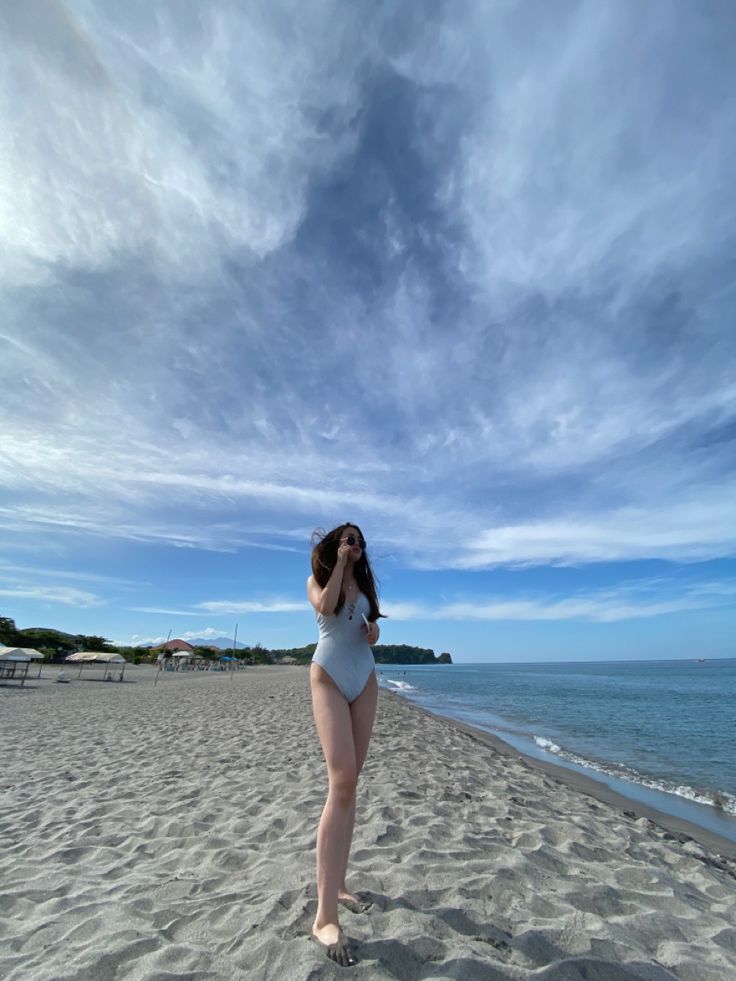 a woman standing on top of a sandy beach