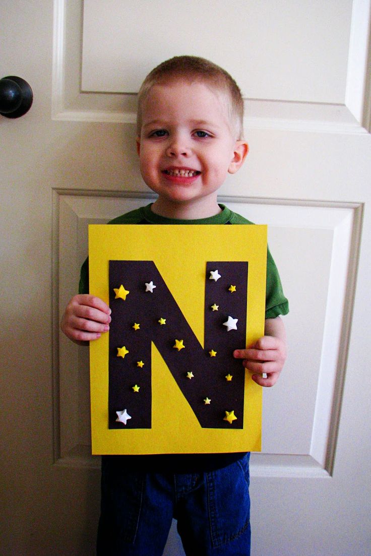 a young boy holding up a letter n craft